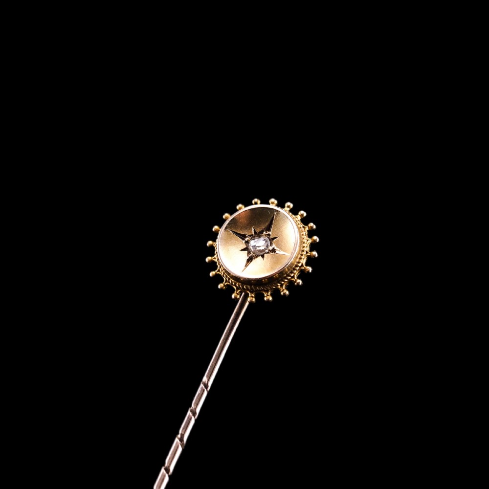 A Victorian 14ct gold stick pin featuring a round head with a star-set diamond and a beaded granulated outer border. View VIII