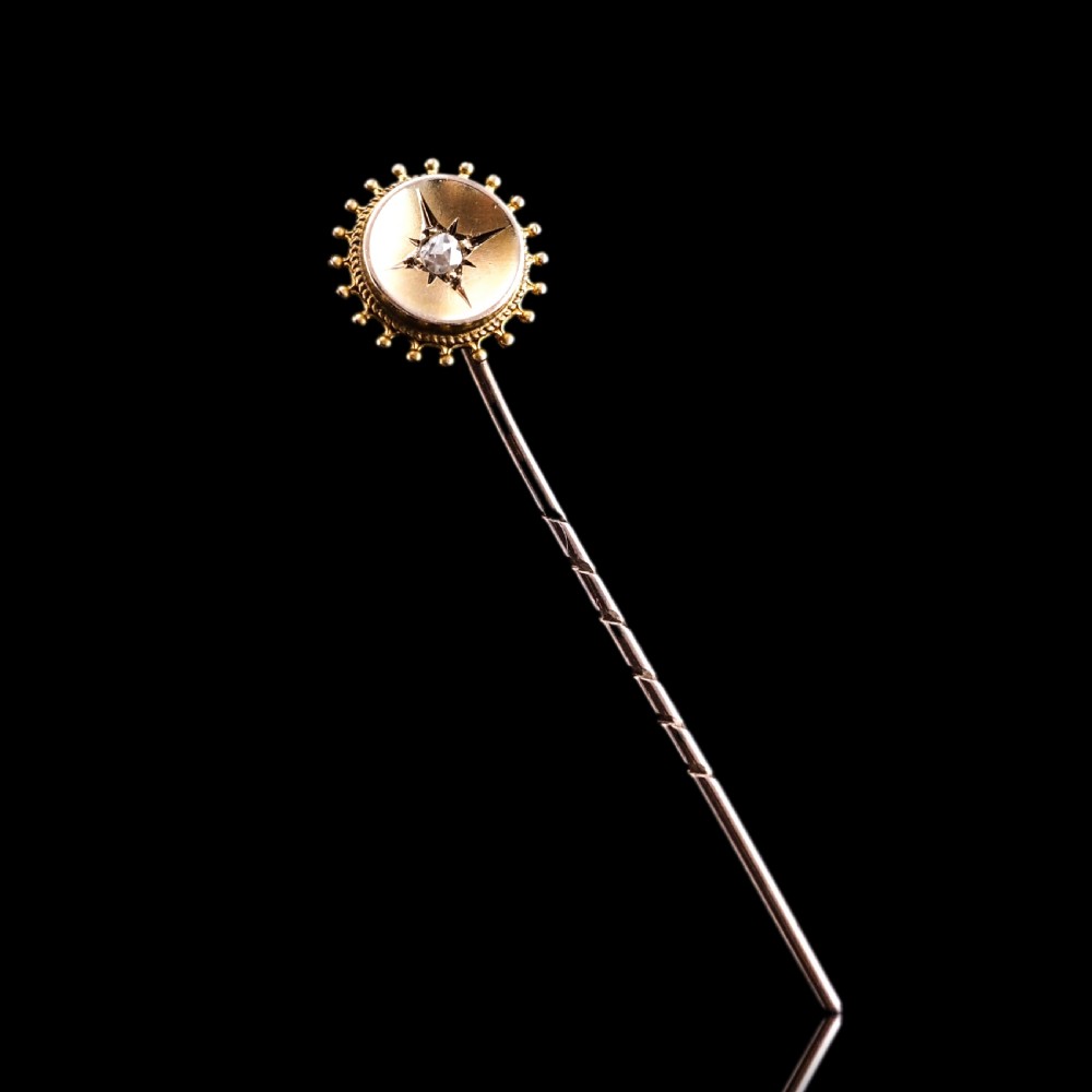 A Victorian 14ct gold stick pin featuring a round head with a star-set diamond and a beaded granulated outer border. View IX