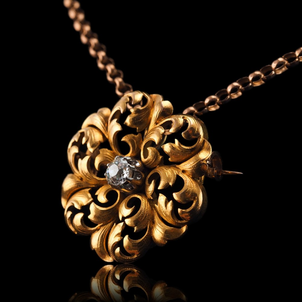 An 18ct yellow gold Victorian pendant brooch with openwork acanthus leaf scrollwork and a central round diamond. View XIX