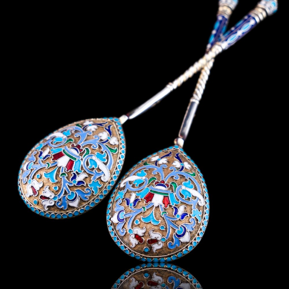 A pair of late nineteenth century Russian solid silver spoons featuring floral cloisonne enamel in turquoise, blue, red, and white on gilded teardrop bowls with twisted handles.