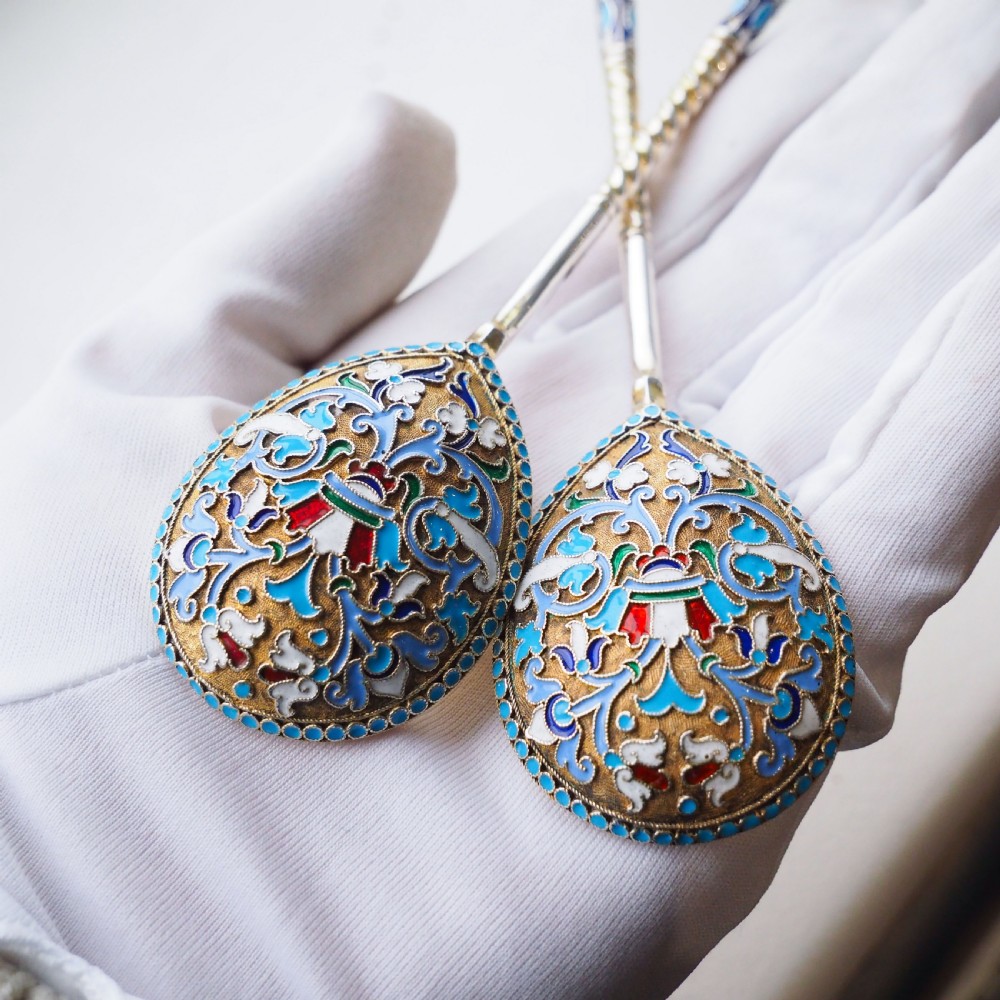 A pair of late nineteenth century Russian solid silver spoons featuring floral cloisonne enamel in turquoise, blue, red, and white on gilded teardrop bowls with twisted handles. View V