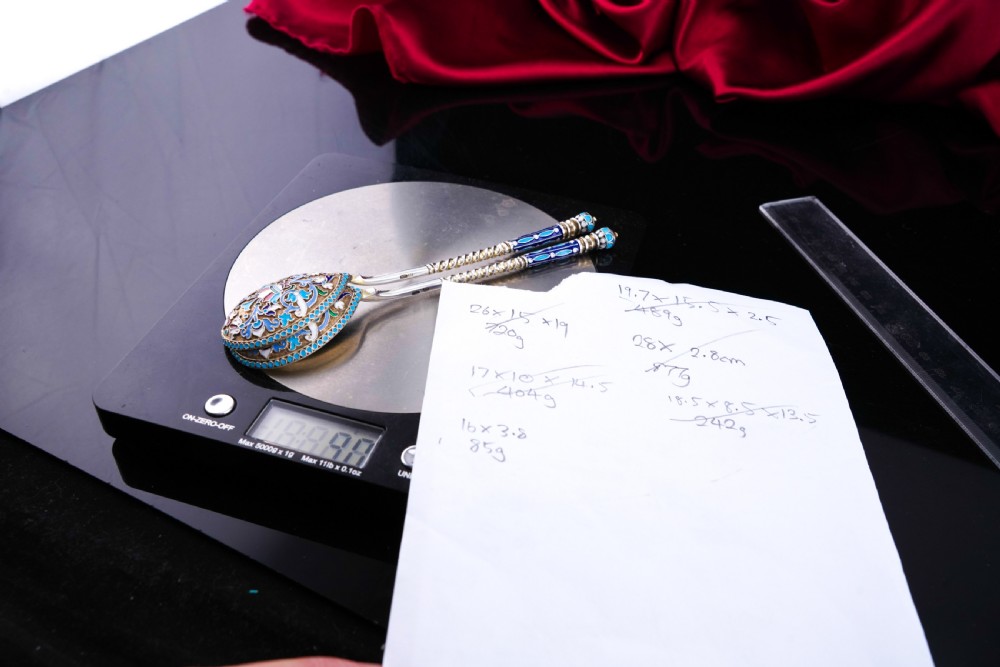 A pair of late nineteenth century Russian solid silver spoons featuring floral cloisonne enamel in turquoise, blue, red, and white on gilded teardrop bowls with twisted handles. View X