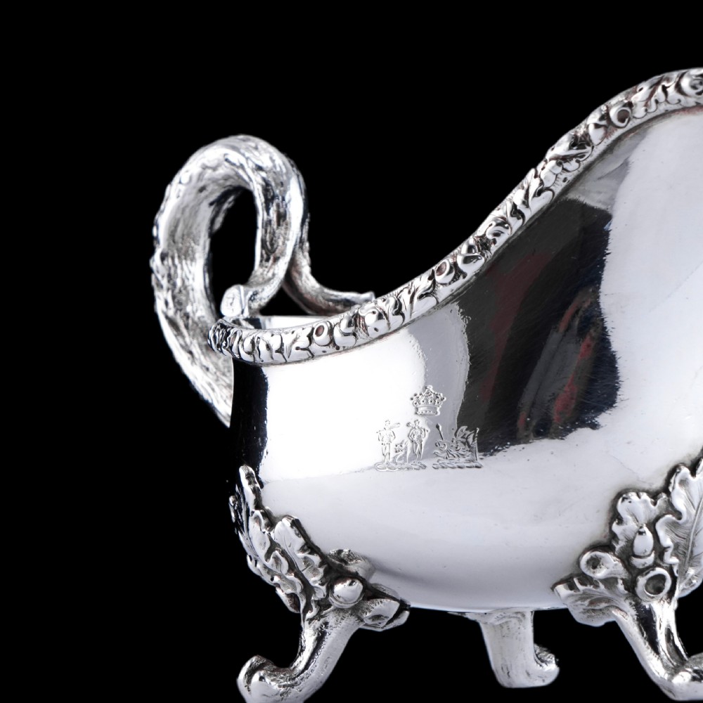 A Victorian sterling silver sauce boat featuring an organic twig handle, acorn feet, and engraved crest detailing. View VII
