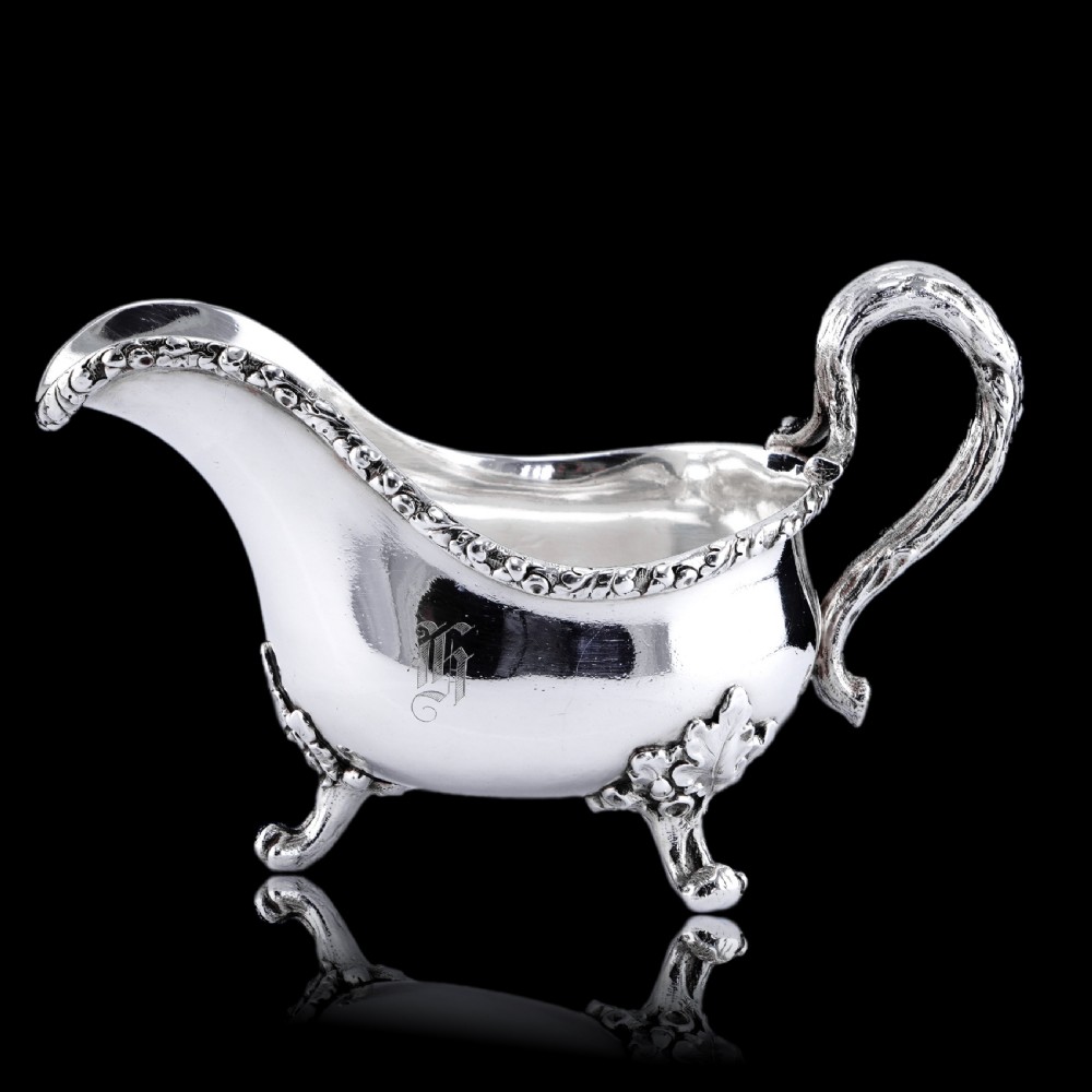 A Victorian sterling silver sauce boat featuring an organic twig handle, acorn feet, and engraved crest detailing. View XVII