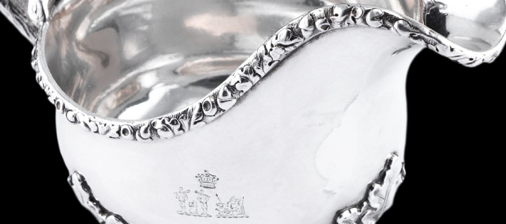 A Victorian sterling silver sauce boat featuring an organic twig handle, acorn feet, and engraved crest detailing. View XIX