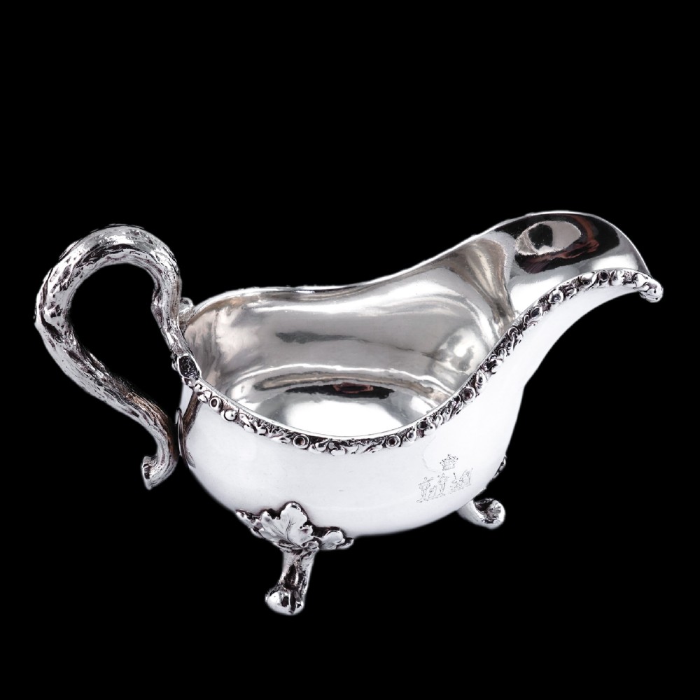 A Victorian sterling silver sauce boat featuring an organic twig handle, acorn feet, and engraved crest detailing. View XXIII