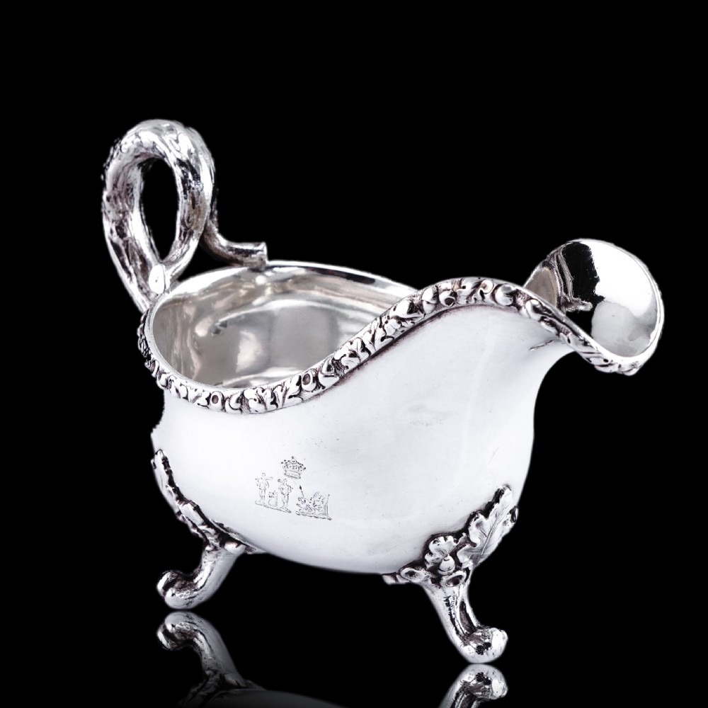 A Victorian sterling silver sauce boat featuring an organic twig handle, acorn feet, and engraved crest detailing. View XXIV
