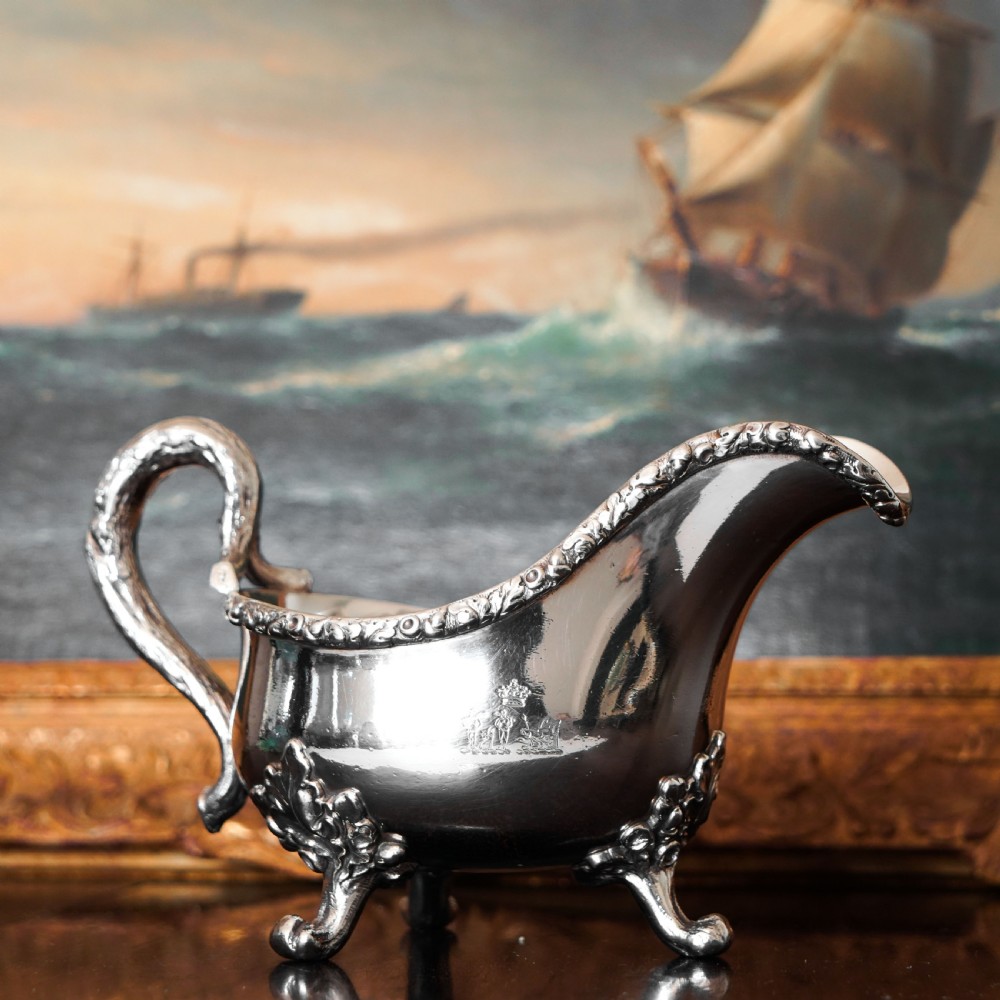 A Victorian sterling silver sauce boat featuring acorn and leaf feet, a branch-formed handle, and an engraved crest. View IV