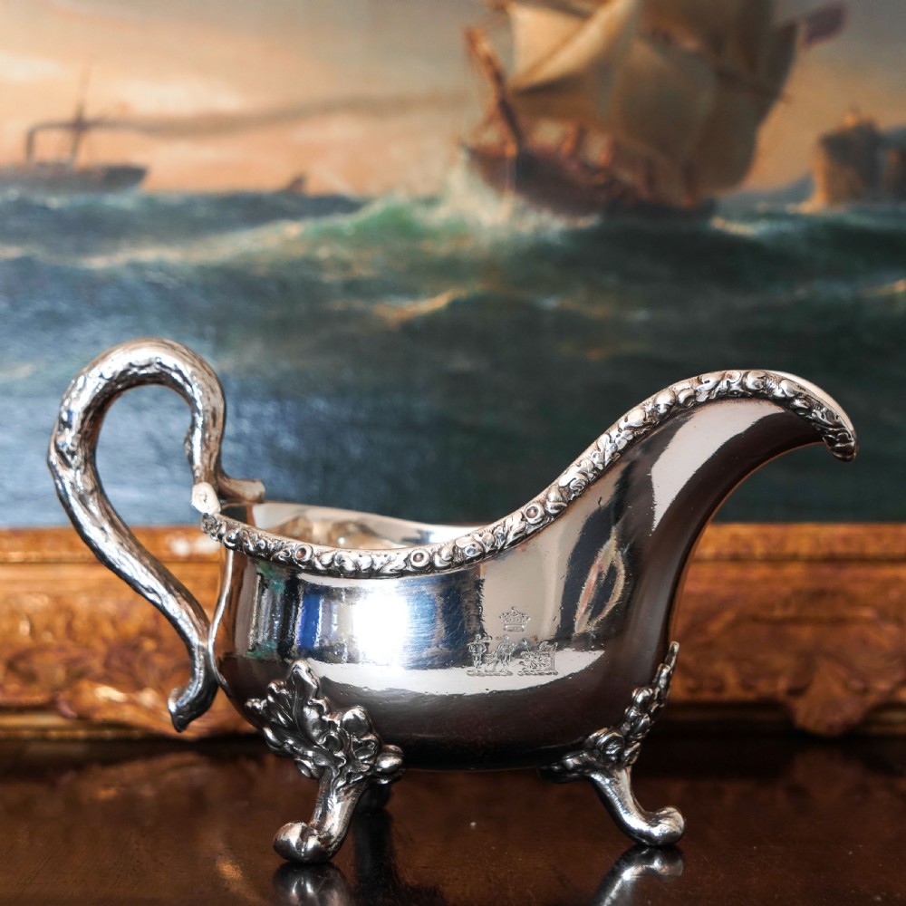 A Victorian sterling silver sauce boat featuring acorn and leaf feet, a branch-formed handle, and an engraved crest. View V