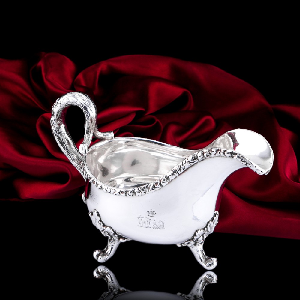 A Victorian sterling silver sauce boat featuring acorn and leaf feet, a branch-formed handle, and an engraved crest. View VI