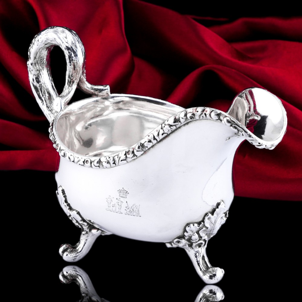 A Victorian sterling silver sauce boat featuring acorn and leaf feet, a branch-formed handle, and an engraved crest. View VII