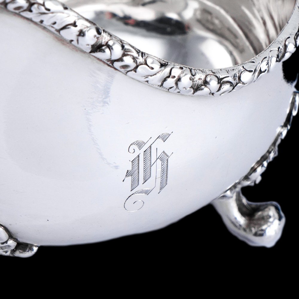 A Victorian sterling silver sauce boat featuring acorn and leaf feet, a branch-formed handle, and an engraved crest. View XIII