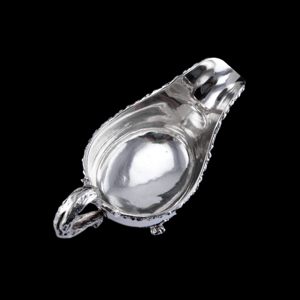 A Victorian sterling silver sauce boat featuring acorn and leaf feet, a branch-formed handle, and an engraved crest. View XV