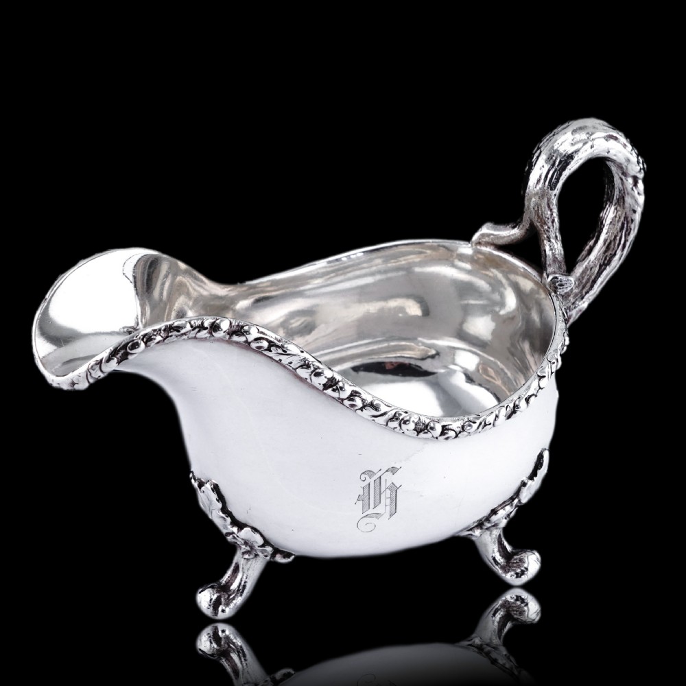 A Victorian sterling silver sauce boat featuring acorn and leaf feet, a branch-formed handle, and an engraved crest. View XXII
