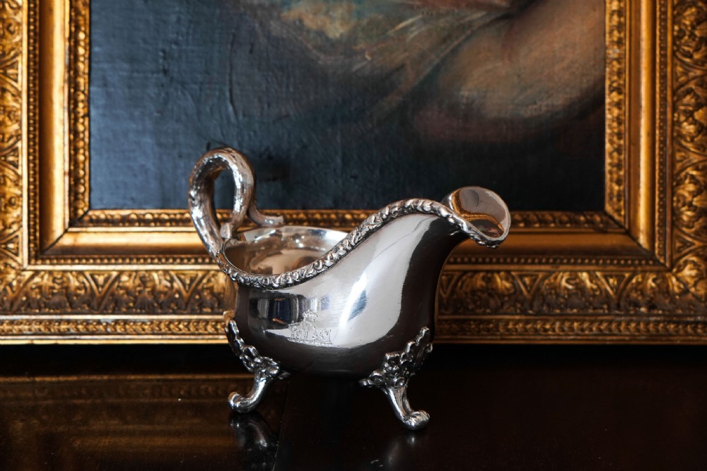 A Victorian sterling silver sauce boat featuring acorn and leaf feet, a branch-formed handle, and an engraved crest. View XXIV