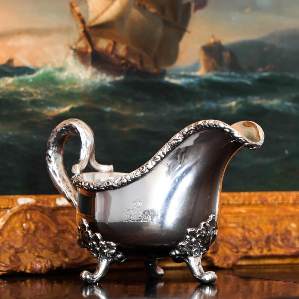 A Victorian sterling silver sauce boat featuring acorn and leaf feet, a branch-formed handle, and an engraved crest. View XXVII