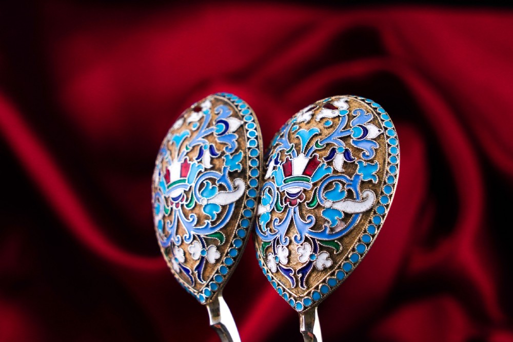 A pair of late 19th-century Russian solid silver spoons featuring turquoise, blue, and white cloisonne enamel foliate decoration on silver-gilt teardrop bowls with twisted handles. View X