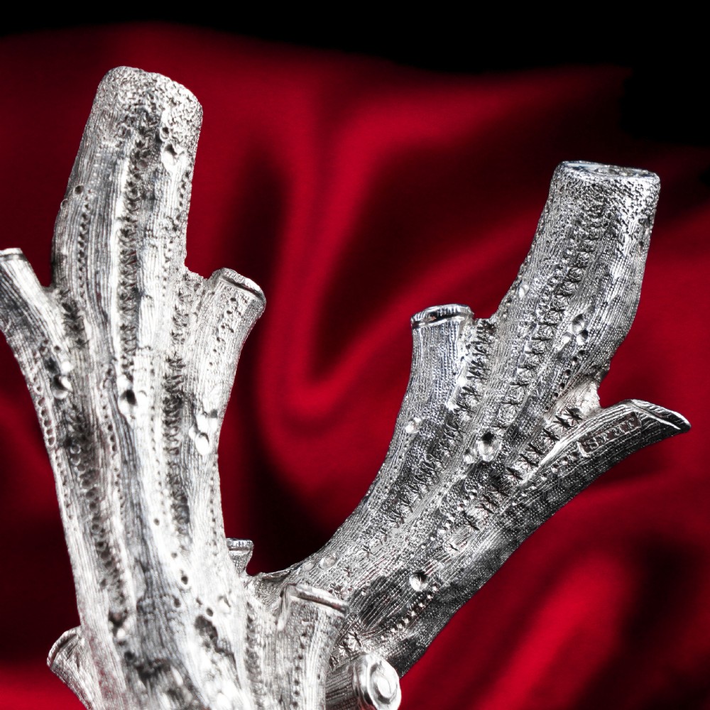 A detailed close-up of a Victorian solid silver knife rest fashioned in the shape of a textured tree branch.