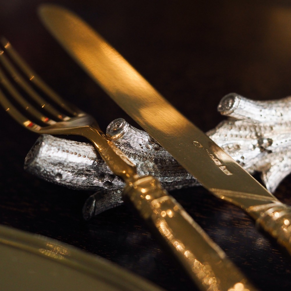A detailed close-up of a Victorian solid silver knife rest fashioned in the shape of a textured tree branch. View III