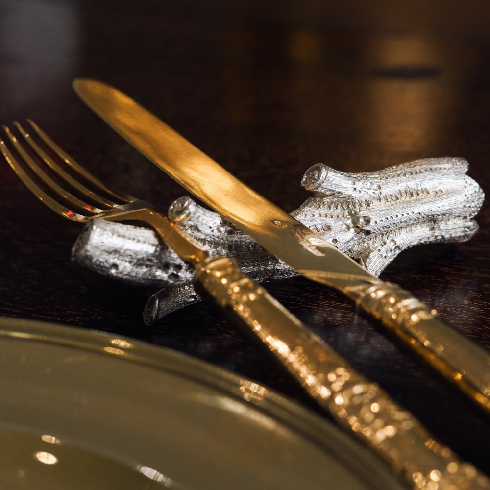 A detailed close-up of a Victorian solid silver knife rest fashioned in the shape of a textured tree branch. View V