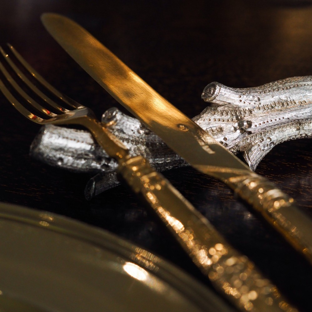 A detailed close-up of a Victorian solid silver knife rest fashioned in the shape of a textured tree branch. View VI