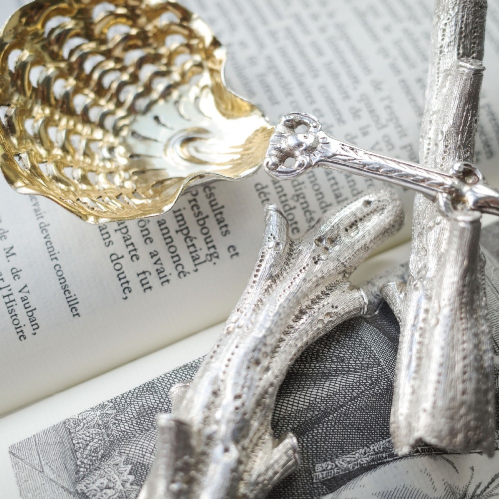 A detailed close-up of a Victorian solid silver knife rest fashioned in the shape of a textured tree branch. View VII