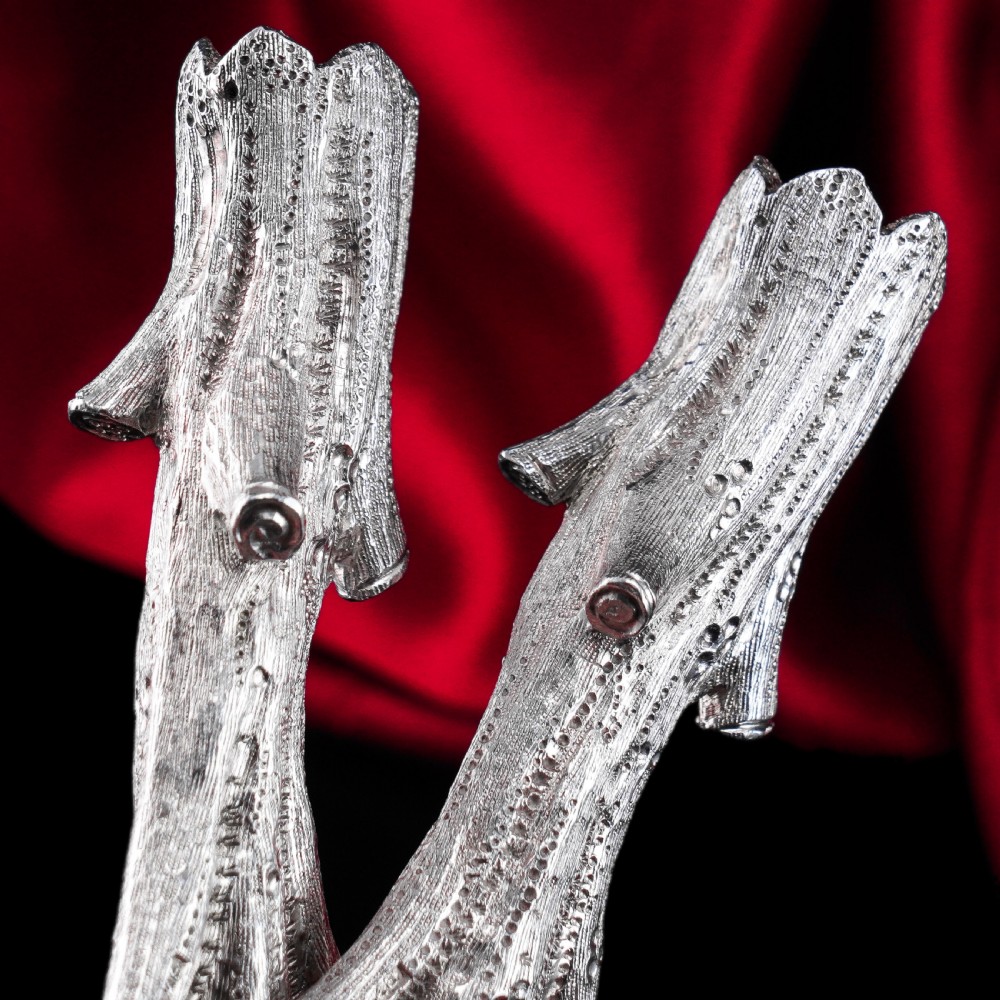 A detailed close-up of a Victorian solid silver knife rest fashioned in the shape of a textured tree branch. View X
