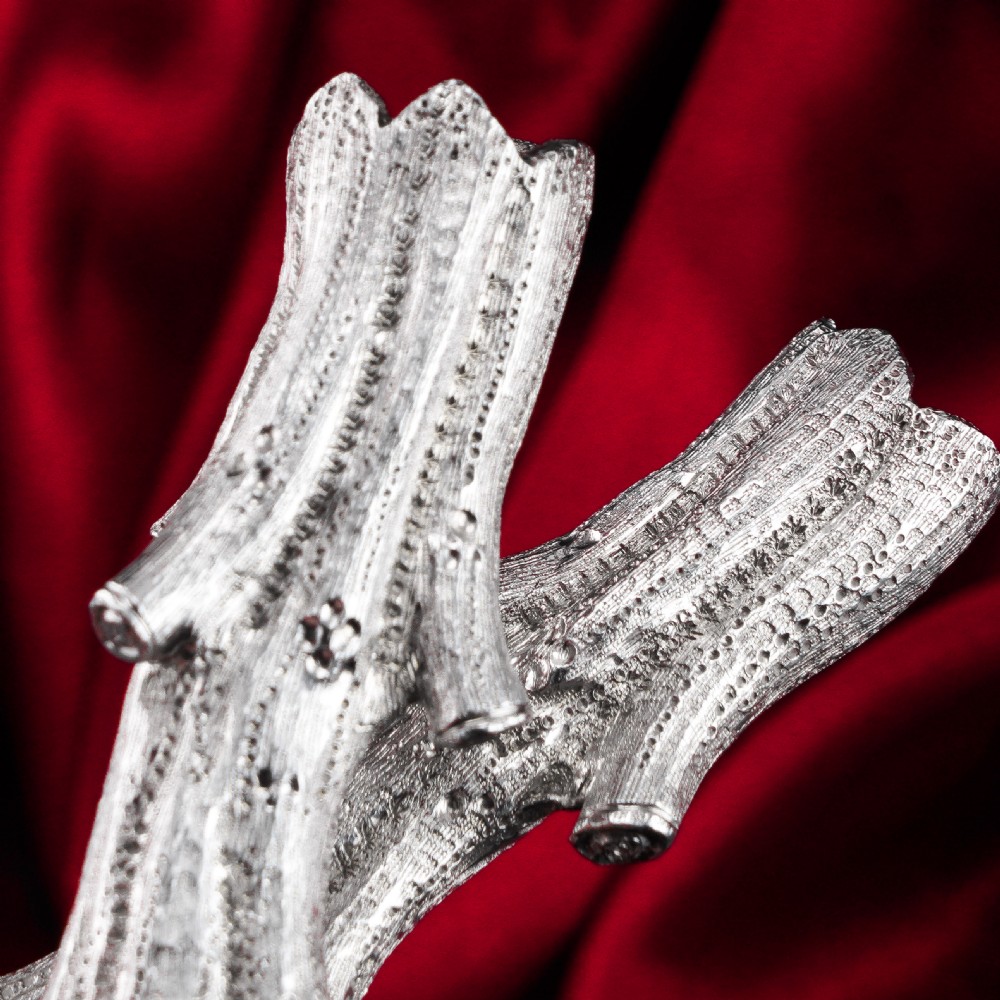 A detailed close-up of a Victorian solid silver knife rest fashioned in the shape of a textured tree branch. View XI