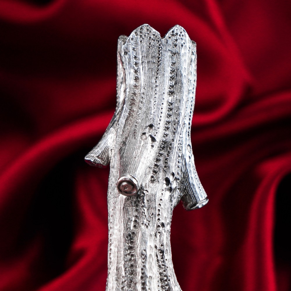 A detailed close-up of a Victorian solid silver knife rest fashioned in the shape of a textured tree branch. View XIII
