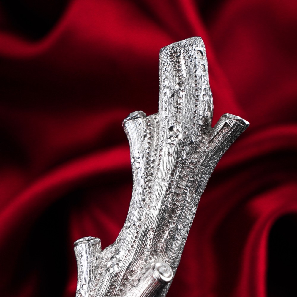 A detailed close-up of a Victorian solid silver knife rest fashioned in the shape of a textured tree branch. View XIV