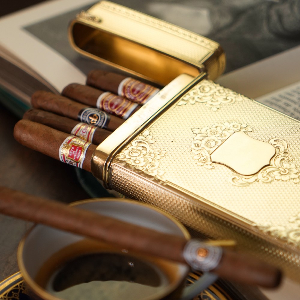 An antique Victorian sterling silver gilt cigar case featuring fine engine-turned texturing, scroll engraving, and a central unengraved cartouche.
