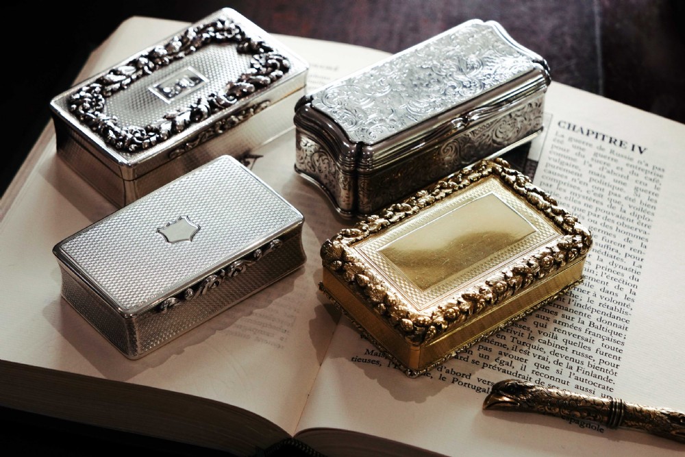 A rectangular Victorian sterling silver snuff box with an open hinged lid, engine-turned engraving, cast acanthus leaf border, and a gilt interior. View II