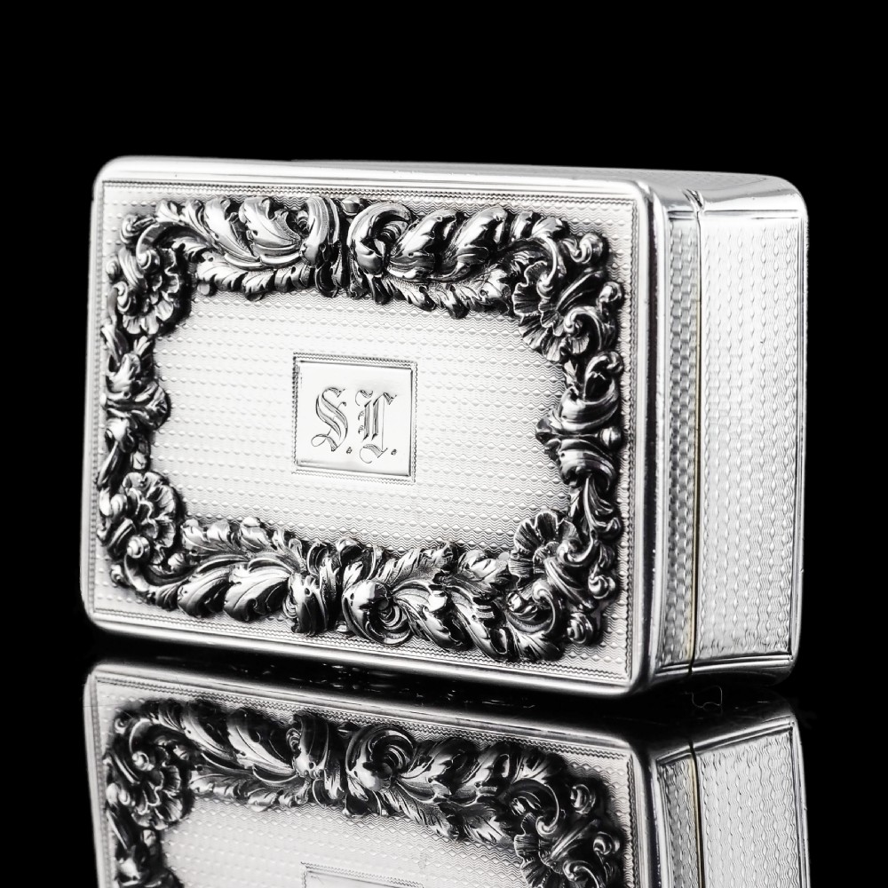 A rectangular Victorian sterling silver snuff box with an open hinged lid, engine-turned engraving, cast acanthus leaf border, and a gilt interior. View III