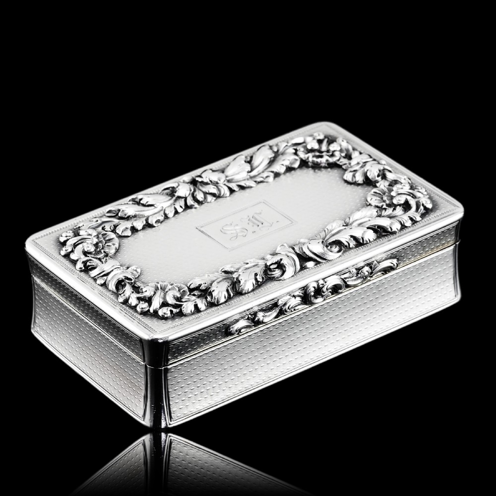 A rectangular Victorian sterling silver snuff box with an open hinged lid, engine-turned engraving, cast acanthus leaf border, and a gilt interior. View VIII