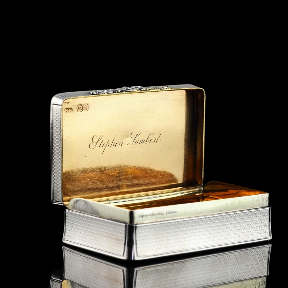 A rectangular Victorian sterling silver snuff box with an open hinged lid, engine-turned engraving, cast acanthus leaf border, and a gilt interior. View XII