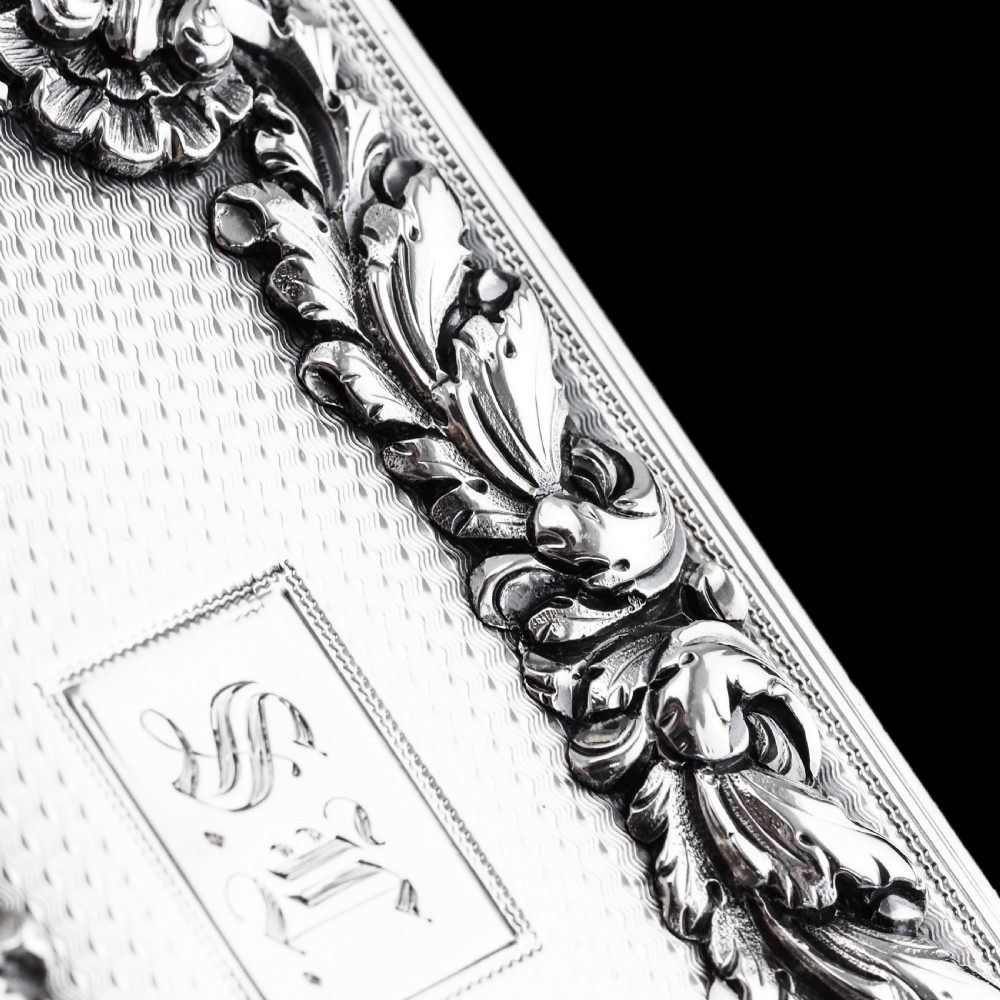 A rectangular Victorian sterling silver snuff box with an open hinged lid, engine-turned engraving, cast acanthus leaf border, and a gilt interior. View XIII