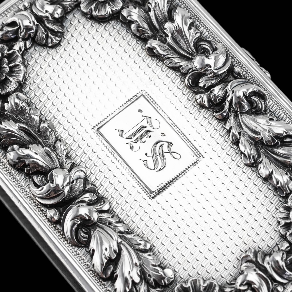 A rectangular Victorian sterling silver snuff box with an open hinged lid, engine-turned engraving, cast acanthus leaf border, and a gilt interior. View XIV