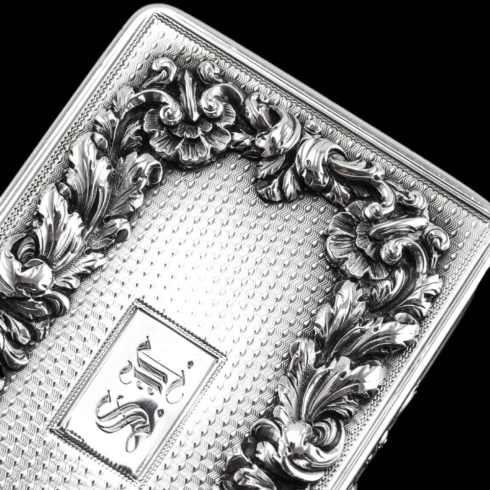 A rectangular Victorian sterling silver snuff box with an open hinged lid, engine-turned engraving, cast acanthus leaf border, and a gilt interior. View XV
