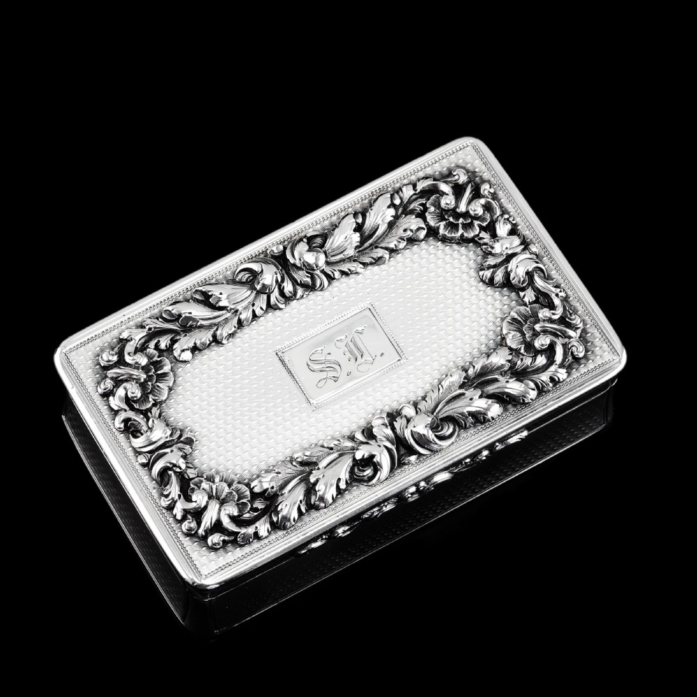 A rectangular Victorian sterling silver snuff box with an open hinged lid, engine-turned engraving, cast acanthus leaf border, and a gilt interior. View XIX