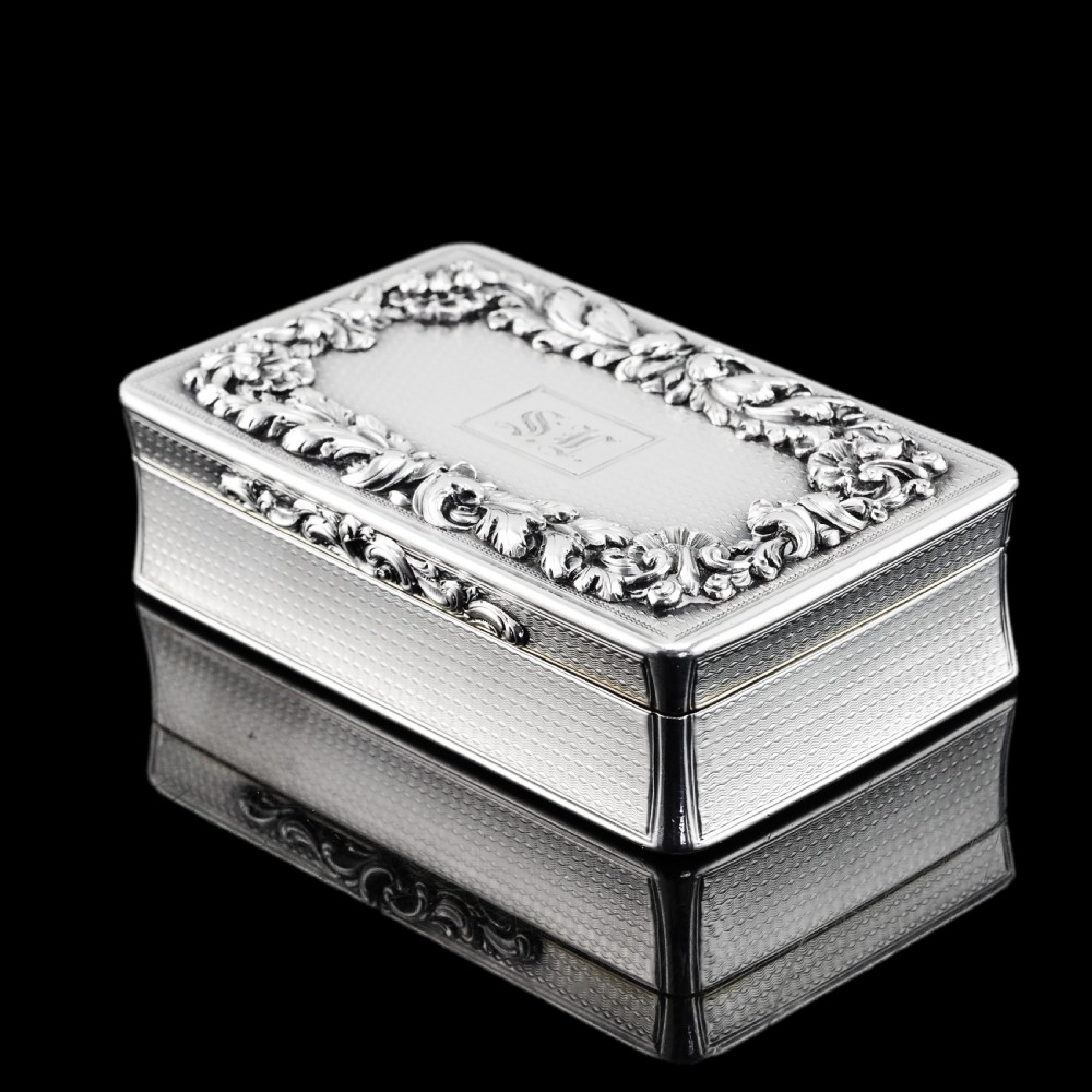 A rectangular Victorian sterling silver snuff box with an open hinged lid, engine-turned engraving, cast acanthus leaf border, and a gilt interior. View XXI