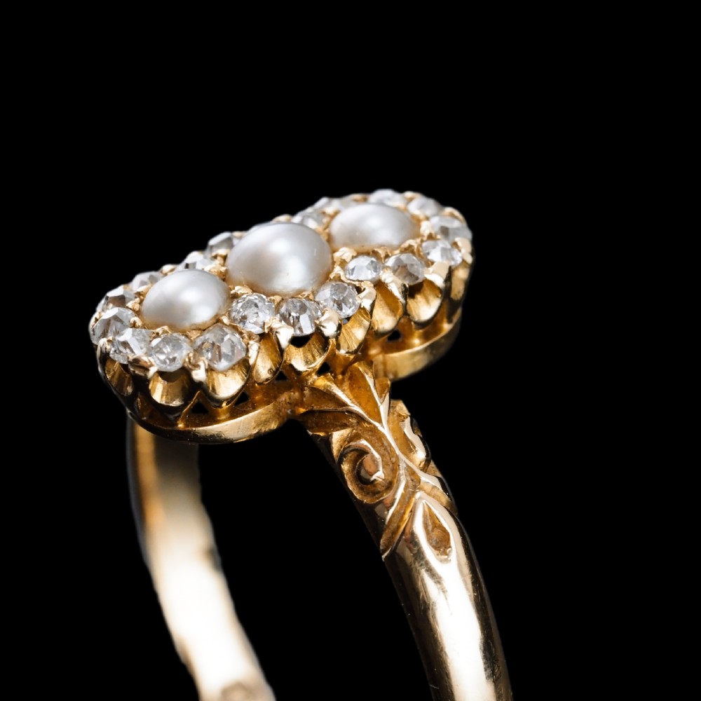 An 18 carat yellow gold ring featuring a vertical triple cluster set with three central pearls surrounded by small diamonds, complete with carved detail on the shoulders. View II