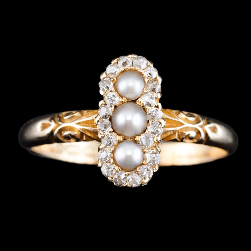 An 18 carat yellow gold ring featuring a vertical triple cluster set with three central pearls surrounded by small diamonds, complete with carved detail on the shoulders. View III
