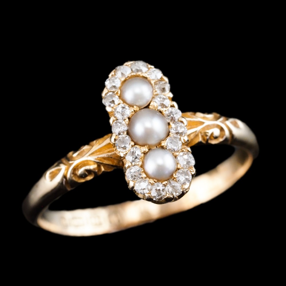 An 18 carat yellow gold ring featuring a vertical triple cluster set with three central pearls surrounded by small diamonds, complete with carved detail on the shoulders. View IV