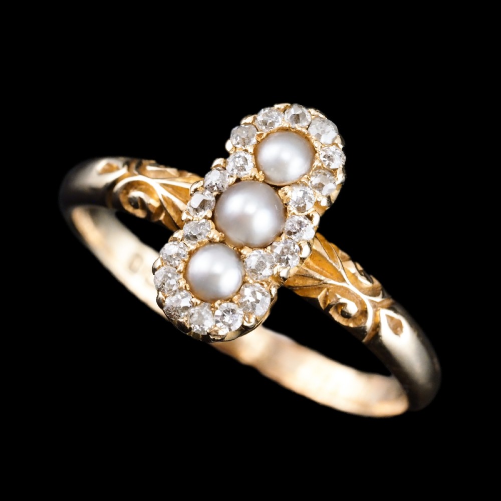 An 18 carat yellow gold ring featuring a vertical triple cluster set with three central pearls surrounded by small diamonds, complete with carved detail on the shoulders. View V
