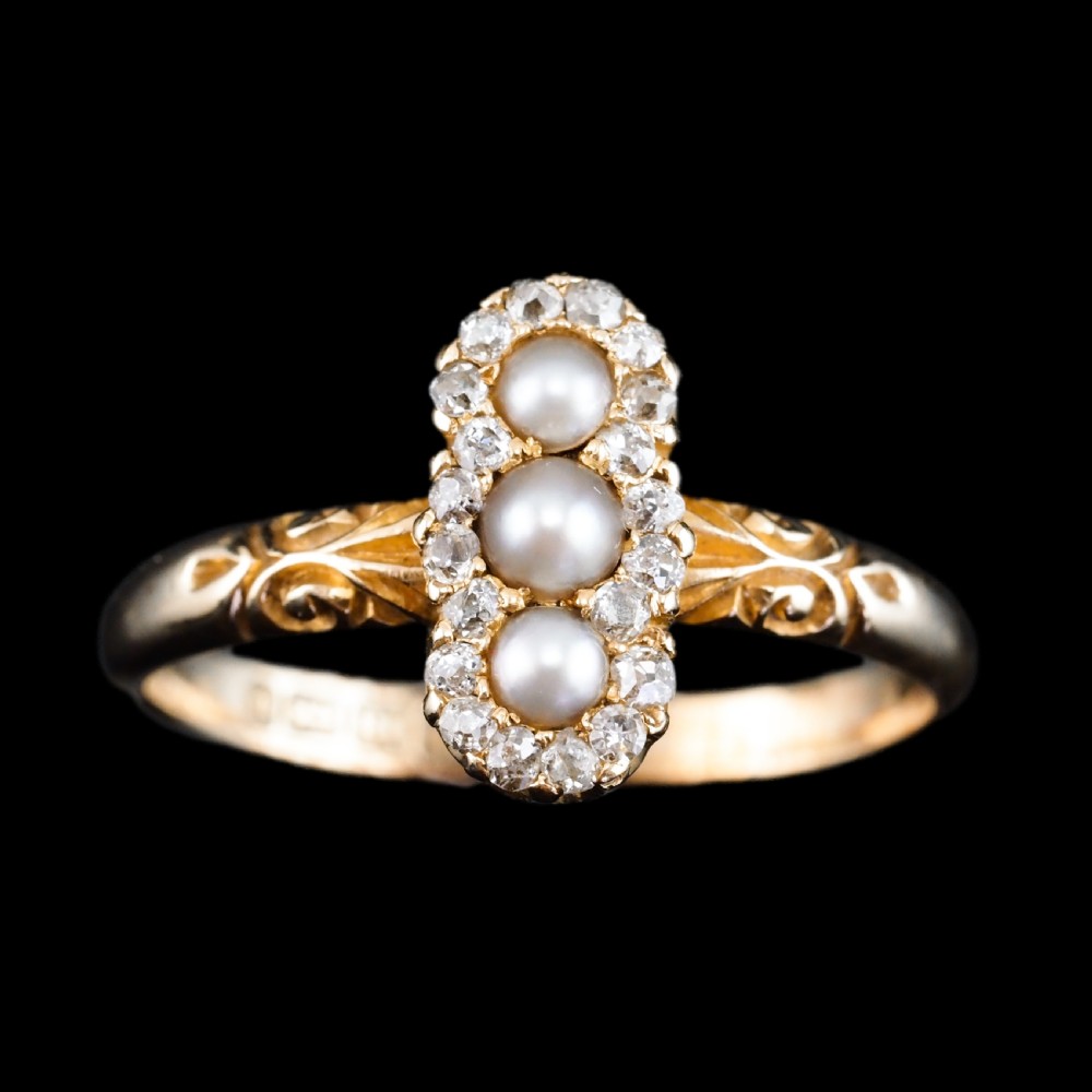 An 18 carat yellow gold ring featuring a vertical triple cluster set with three central pearls surrounded by small diamonds, complete with carved detail on the shoulders. View VIII