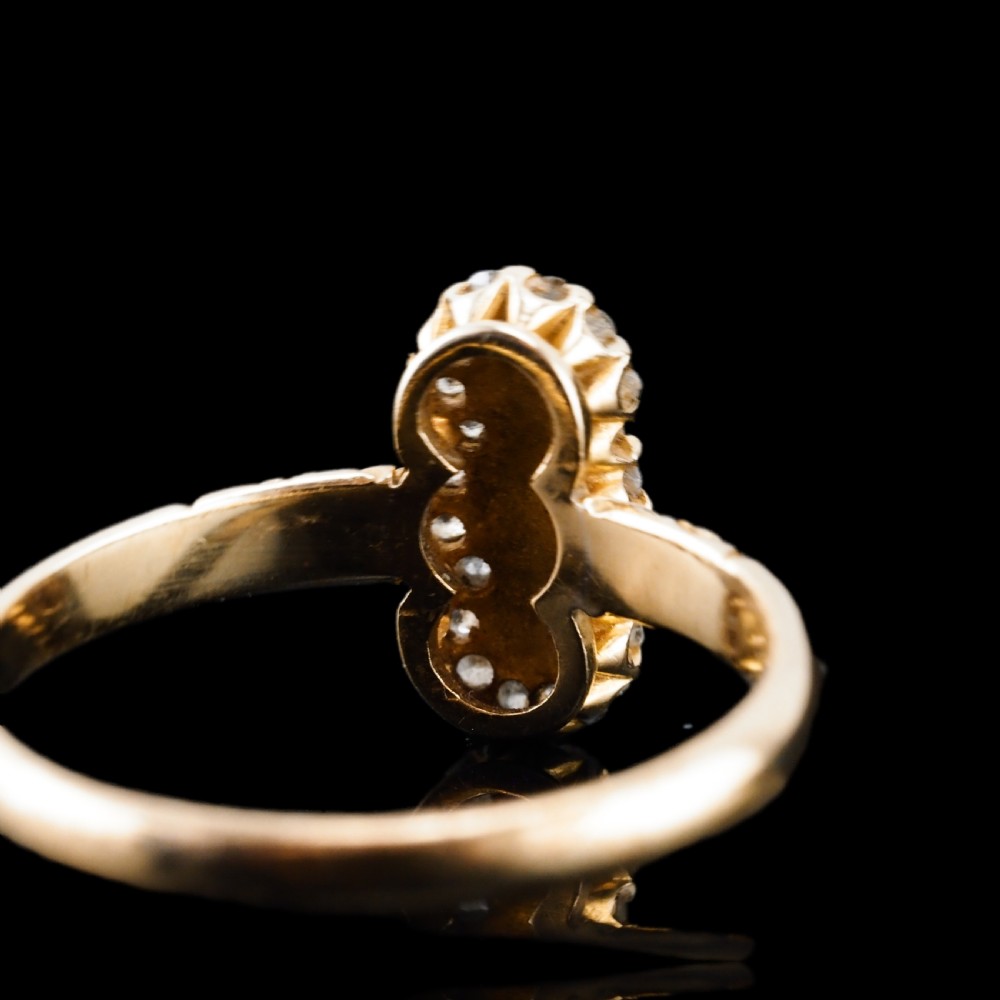 An 18 carat yellow gold ring featuring a vertical triple cluster set with three central pearls surrounded by small diamonds, complete with carved detail on the shoulders. View IX