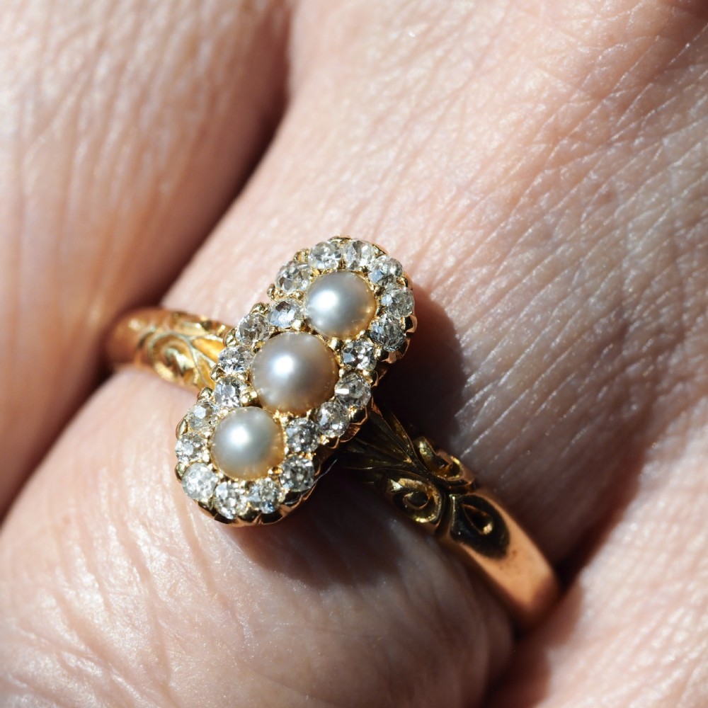 An 18 carat yellow gold ring featuring a vertical triple cluster set with three central pearls surrounded by small diamonds, complete with carved detail on the shoulders. View XII