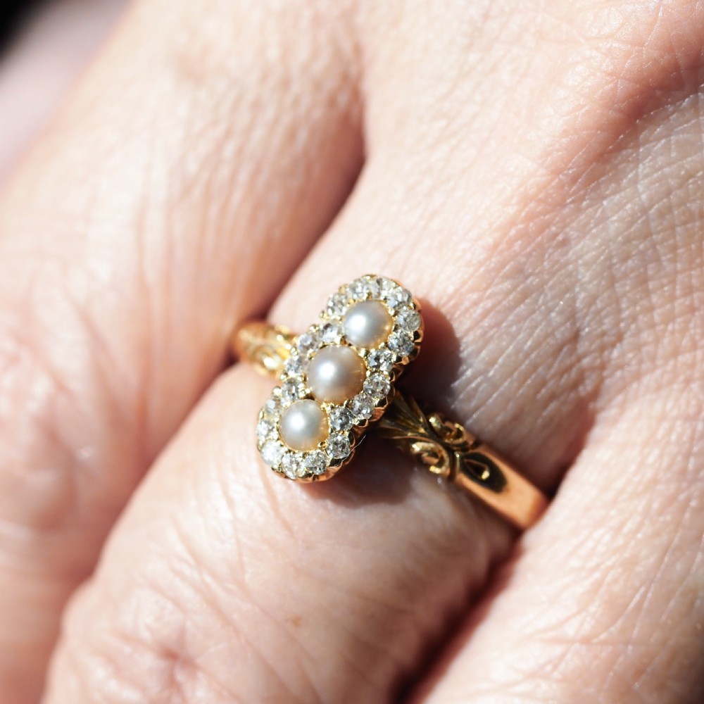 An 18 carat yellow gold ring featuring a vertical triple cluster set with three central pearls surrounded by small diamonds, complete with carved detail on the shoulders. View XIII
