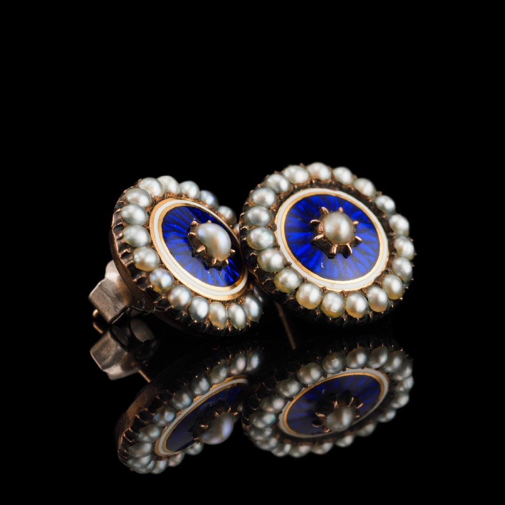 A pair of Georgian circular gold earrings featuring cobalt blue guilloche enamel centres surrounded by concentric rings of white enamel and seed pearls. View VI