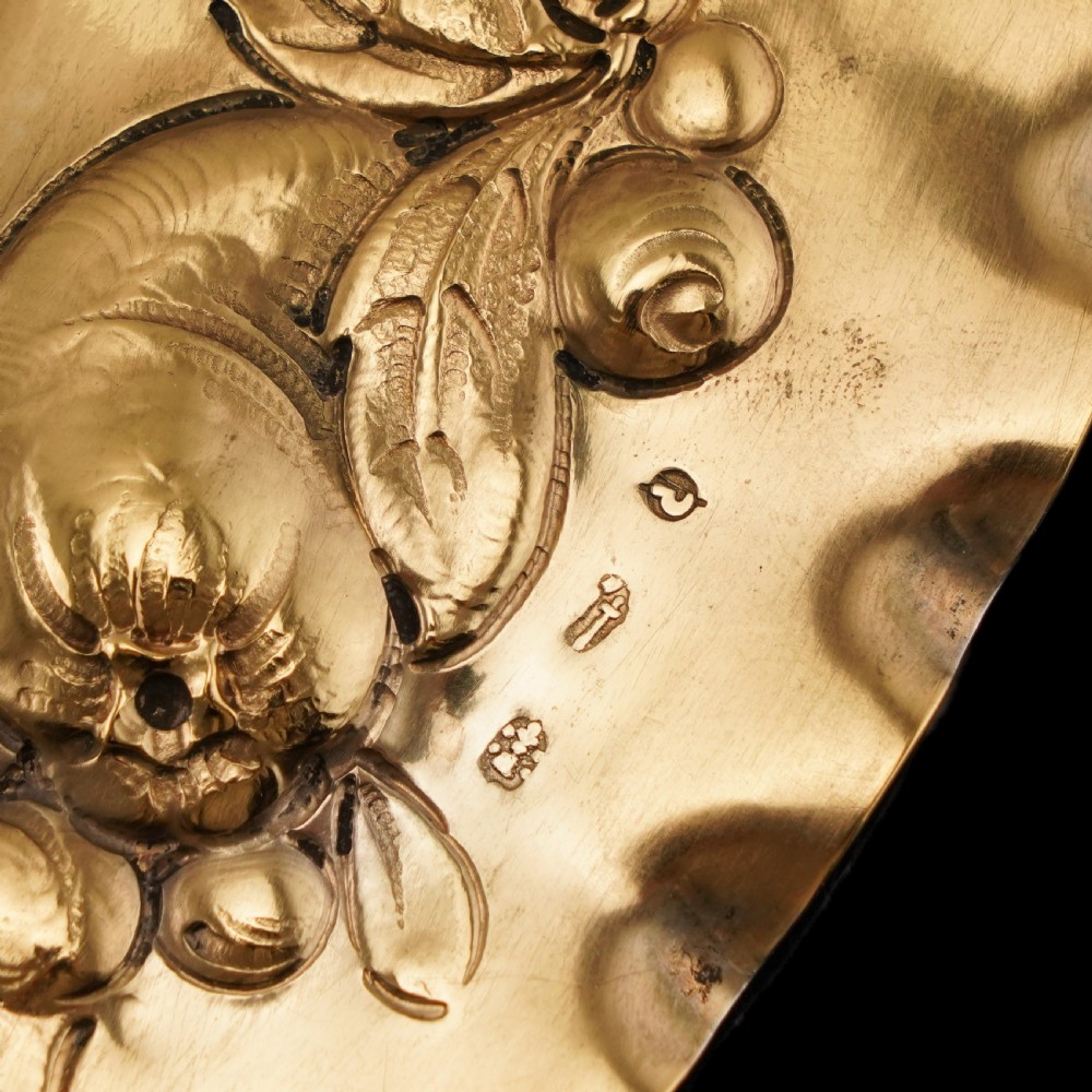 An oval 19th-century solid silver gilt charger dish featuring a central raised relief of a battle scene surrounded by embossed fruit borders. View XXI